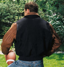 Load image into Gallery viewer, Back Smiling young man in a varsity jacket holding a football, ready for a game.
