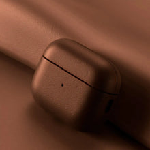 Load image into Gallery viewer, Genuine leather AirPods case in brown, showcasing elegant protection and style on a leather background.
