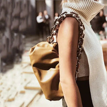 Load image into Gallery viewer, Woman wearing a stylish soft leather cloud bag with chain strap, complemented by a white sleeveless sweater for a chic look.
