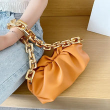 Load image into Gallery viewer, Soft leather women&#39;s cloud bag with gold chain resting on denim, showcasing luxury and elegance.
