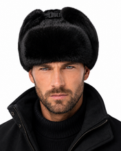 Load image into Gallery viewer, A close-up of a man wearing a black fur ushanka hat and a black jacket against a plain white background.
