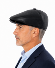 Load image into Gallery viewer, A man in profile wearing a black leather flat cap, light blue dress shirt, and navy blazer against a solid white background.
