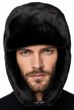 Load image into Gallery viewer, A man wearing a black faux fur ushanka hat with ear flaps, shown from the chest up against a plain white background.
