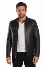 Load image into Gallery viewer, A man wearing a black leather biker jacket over a white t-shirt and black pants, standing against a plain white background.

