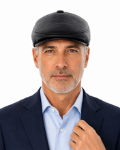 Load image into Gallery viewer, A man wearing a black leather flat cap, a light blue dress shirt, and a navy blue blazer, photographed against a solid white background.
