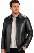 Charger l'image dans la galerie, A man wearing a black leather jacket over a light beige t-shirt and black pants, photographed against a solid white background.
