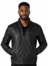 Cargar imagen en el visor de la galería, A man wearing a black leather jacket with a front zipper, stand-up collar, and zippered hand pockets, paired with a black shirt and dark jeans, photographed against a plain white background.
