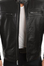 Load image into Gallery viewer, A man wearing a black leather motorcycle jacket over a white t-shirt and black pants, shown from the chin down against a plain white background.
