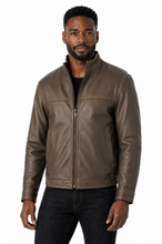 Cargar imagen en el visor de la galería, A man wearing a brown leather jacket with a front zipper, stand-up collar, and zippered hand pockets, paired with a black shirt and black jeans, against a plain white background.
