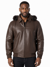 Load image into Gallery viewer, A man wearing a brown real-leather hooded jacket with a dark fur trimmed hood, shown against a plain white background.
