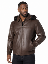 Load image into Gallery viewer, A man wearing a brown real -leather hooded jacket with a dark real -fur trimmed hood, ribbed knit cuffs and hem, and a front zipper, photographed against a plain white background.
