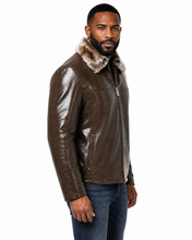 Load image into Gallery viewer, A man wearing a brown textured leather jacket with a brown and white faux fur collar, paired with blue jeans, photographed against a solid white background.
