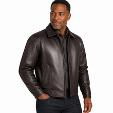 Charger l'image dans la galerie, A man wearing a dark brown leather jacket over a black button-down shirt and dark jeans, photographed against a plain white studio background.
