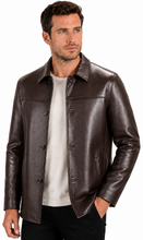 Charger l'image dans la galerie, A man wearing a dark brown leather jacket over a light gray t-shirt and black pants, photographed against a plain white background.
