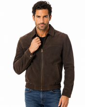 Charger l'image dans la galerie, A man wearing a dark brown suede zip-up jacket over a black shirt and blue jeans, photographed against a plain white background.
