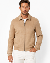 Charger l'image dans la galerie, A man wearing a tan suede-like zip-up jacket with a collar and ribbed cuffs, paired with white pants, photographed against a clean white studio background.
