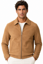 Charger l'image dans la galerie, A man wearing a tan suede zip-up jacket over a white t-shirt and white pants, standing against a plain white background.
