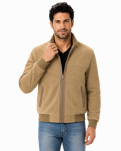 Load image into Gallery viewer, A man wearing a tan zip-up jacket with ribbed knit collar, cuffs, and hem, styled over a black t-shirt and blue jeans, against a plain white background.
