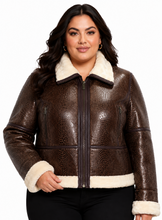 Cargar imagen en el visor de la galería, A woman modeling a brown textured real-leather jacket with a cream sherpa collar, hem, and cuffs, paired with black pants against a white background.
