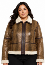 Cargar imagen en el visor de la galería, A woman modeling a cropped brown faux-snakeskin bomber jacket with a cream sherpa collar, front zipper, and matching cream cuffs and hem, paired with black pants against a white background.
