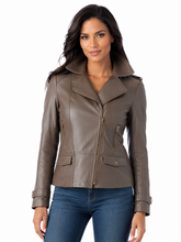 Load image into Gallery viewer, A woman modeling a taupe brown real leather moto jacket with a collar, front zipper, and flap pockets, paired with blue jeans against a white background.

