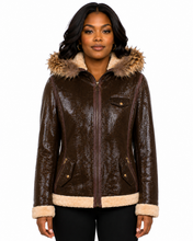 Charger l'image dans la galerie, A woman wearing a dark brown textured real-leather jacket with a beige sherpa lining and a matching faux-fur trimmed hood, shown against a plain white background.
