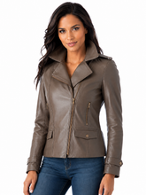 Load image into Gallery viewer, A woman wearing a taupe-brown real leather moto jacket with a high collar and front zipper, paired with blue jeans, against a plain white background.
