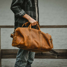 Load image into Gallery viewer, The Dagny Weekender | Large Leather Duffle Bag held by person outdoors, showcasing style and functionality for travelers.
