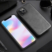 Load image into Gallery viewer, Luxury leather iPhone case with protective hybrid design, showcasing elegance and durability on a wooden surface with accessories.
