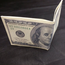 Cargar imagen en el visor de la galería, Folding $100 bill on a dark fabric background
