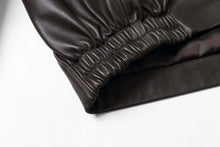 Load image into Gallery viewer, Close-up of REED Men&#39;s New Zealand Lambskin Leather Jacket sleeve showing soft, black lambskin leather texture and craftsmanship.
