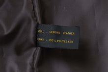 Load image into Gallery viewer, Close-up of a Genuine Leather and 100% Polyester label inside a REED men&#39;s lambskin jacket.
