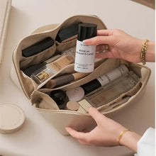 Load image into Gallery viewer, Person organizing makeup products in a beige high-capacity leather cosmetic organizer with multiple compartments.
