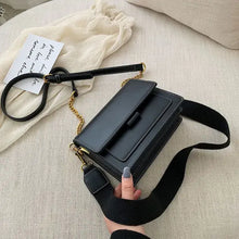 Load image into Gallery viewer, Luxury designer leather crossbody shopping bag with gold accents on a cream sofa, held by a hand, showcasing chic fashion style.
