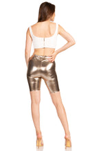 Charger l&#39;image dans la galerie, Back view of model wearing shiny metallic bike shorts with white top, highlighting stretchy fabric, unisex fit, made in USA.
