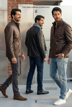 Load image into Gallery viewer, Man modeling a brown leather jacket with a clothing brand logo in the background
