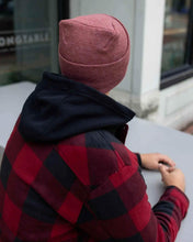 Charger l&#39;image dans la galerie, Person wearing NEW HAAKWEAR H-Stitch Cuffed Beanie - Designed and Made in USA (Patented Design) - Rusty Burgundy, sitting outside.
