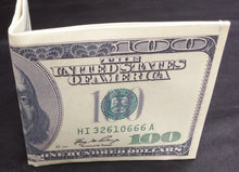 Cargar imagen en el visor de la galería, Origami money folding of a $100 bill on a dark fabric background
