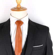 Load image into Gallery viewer, Brown polyurethane leather tie for men paired with a black suit on a mannequin, showcasing vegan fashion elegance.
