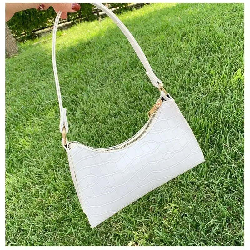 White crocodile pattern PU leather women's shoulder bag on grass, featuring a stylish design perfect for any occasion.