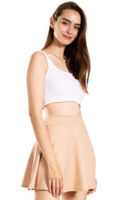 Load image into Gallery viewer, Woman wearing a basic versatile stretchy flared casual mini skater skirt in beige, paired with a white crop top, showcasing a stylish outfit.
