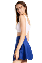 Load image into Gallery viewer, Woman wearing a blue flared mini skater skirt with a white crop top, showcasing a casual versatile style.
