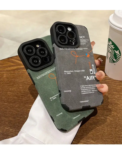 Two Luxury Leather Sneaker Phone Cases with sleek design and suede labels held over a wooden table next to a Starbucks cup.