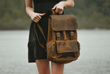Load image into Gallery viewer, A person holding The Hagen Backpack | Vintage Leather Backpack in genuine cowhide with antique finish, ideal for carrying daily essentials.
