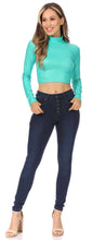 Load image into Gallery viewer, Woman wearing teal matte liquid mock neck turtleneck long sleeve crop top, paired with dark blue high-waisted jeans.
