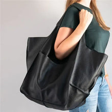 Cargar imagen en el visor de la galería, Woman holding a soft luxury vegan leather shoulder bag, showcasing its large capacity and elegant design.
