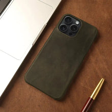 Cargar imagen en el visor de la galería, Genuine leather iPhone case with vintage aesthetic, shown next to a laptop and pen, offering sophisticated protection and style.
