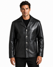 Cargar imagen en el visor de la galería, A man wearing a black leather jacket with silver-tone snap buttons over a black shirt, photographed against a plain white studio background.
