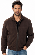 Load image into Gallery viewer, A man wearing a dark brown zip-up suede jacket over a black t-shirt and blue jeans, standing against a plain white background.
