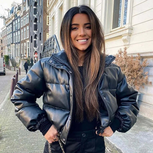Woman wearing a black winter thick PU leather coat, smiling outdoors on a city street, showcasing cozy and stylish fashion.